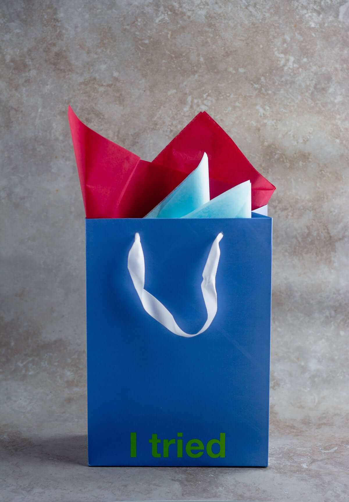 Blue gift bag with the text 'I tried' and colorful tissue paper, part of a funny gift bags set.