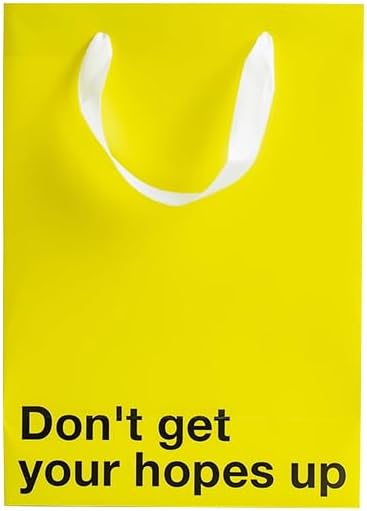 Funny gift bag in bright yellow with text 'Don't get your hopes up' and white ribbon handle.