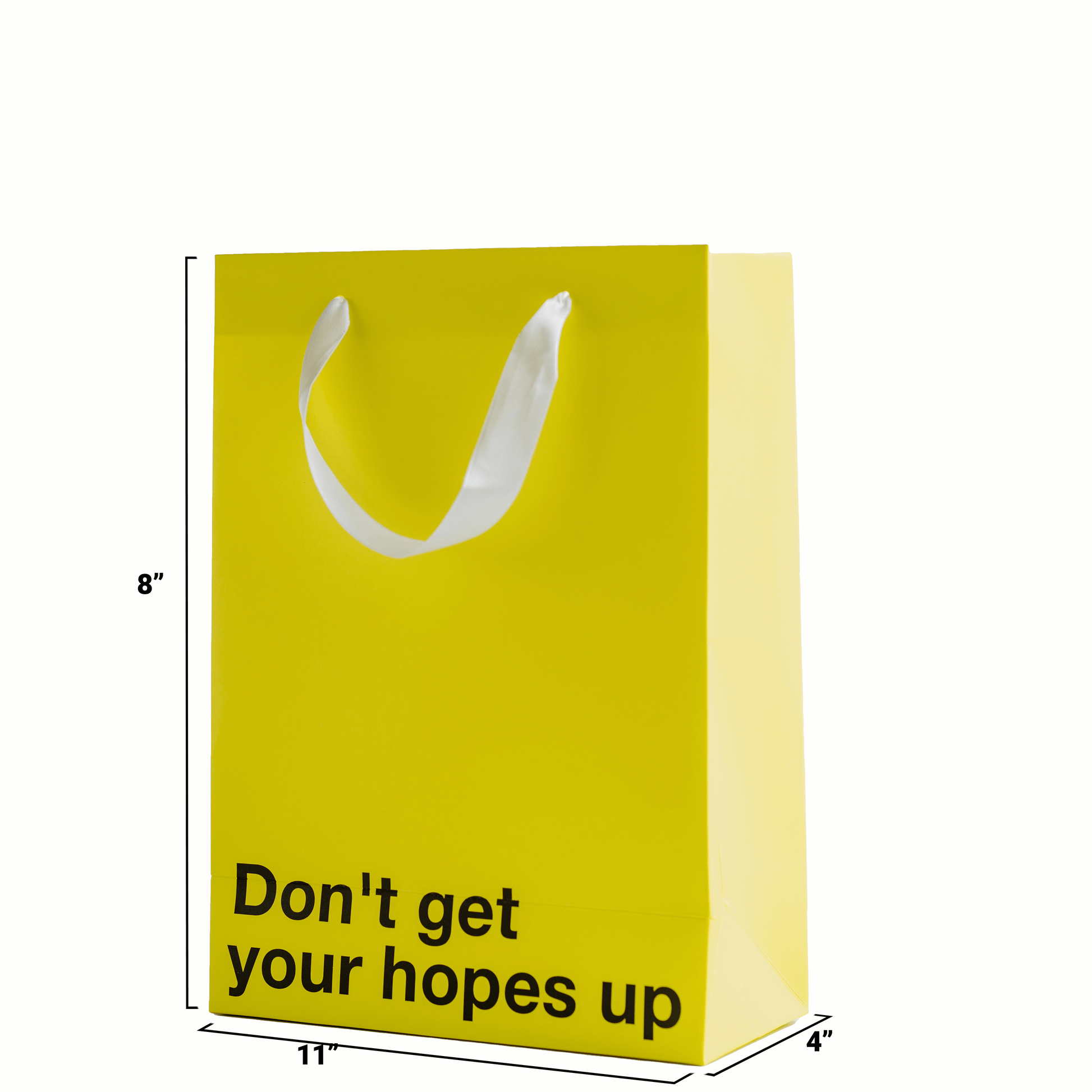 Yellow 'Don't Get Your Hopes Up' funny gift bag with white ribbon handle, size 11 x 8 x 4 inches.