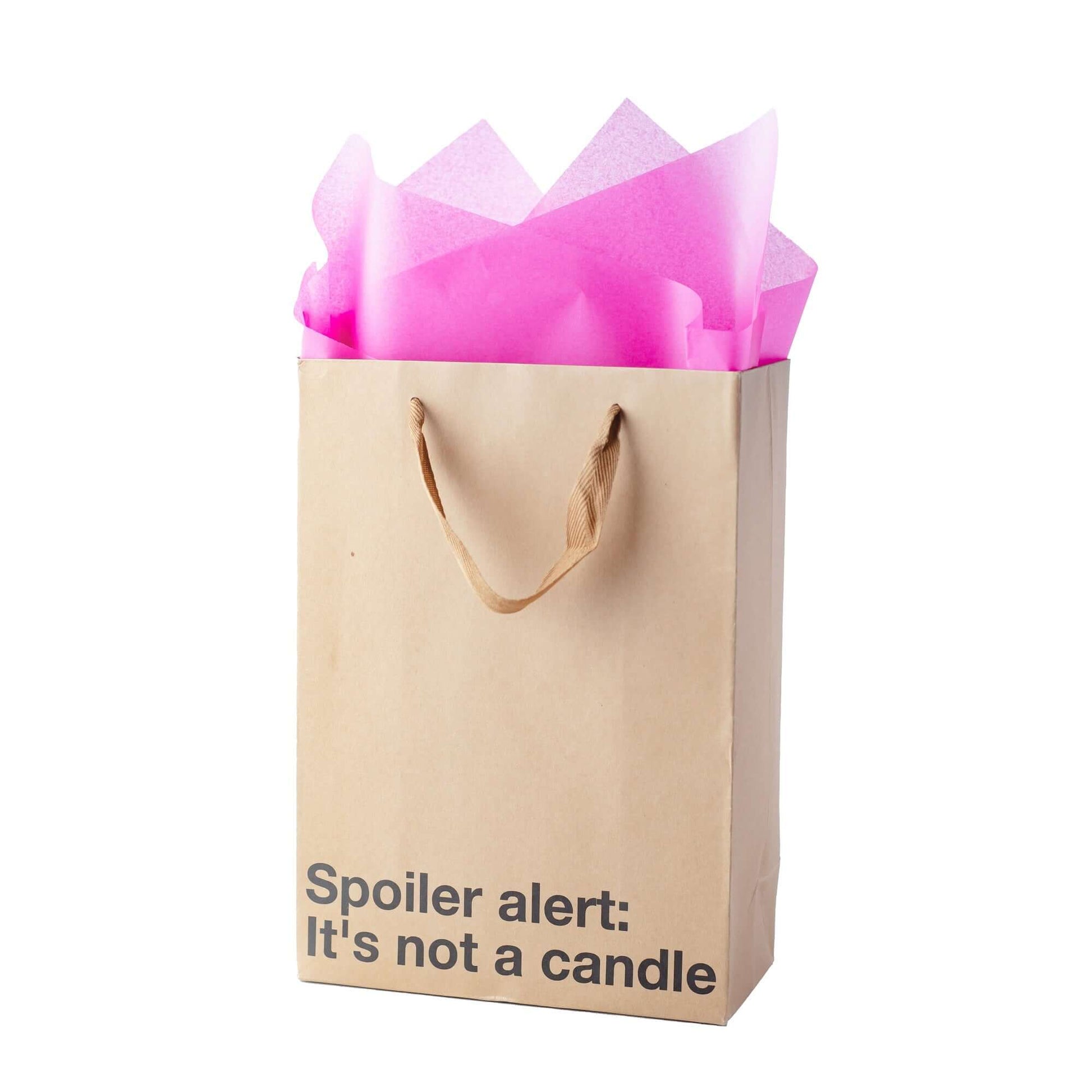 Funny gift bag with pink tissue paper, labeled 'Spoiler alert: It's not a candle,' in kraft material and ribbon handle.