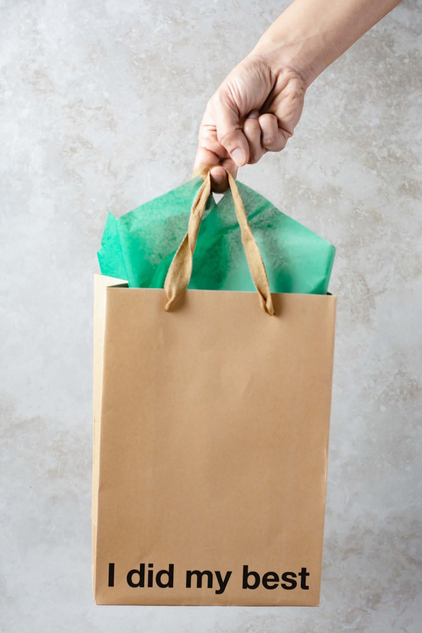 Funny gift bag with the phrase 'I did my best' and green tissue paper, held by a hand.