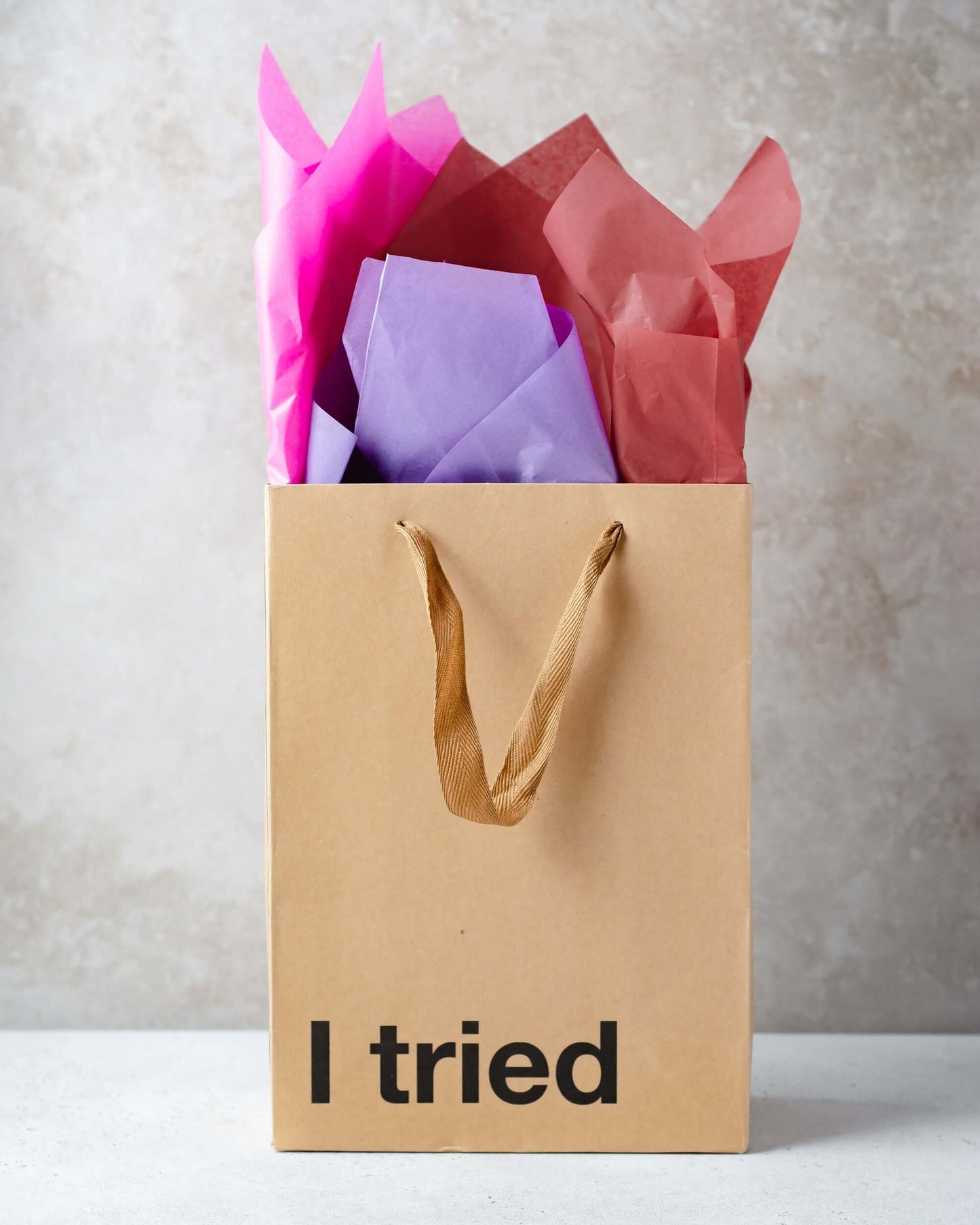 Funny gift bag featuring kraft material with colorful tissue paper peeking out.