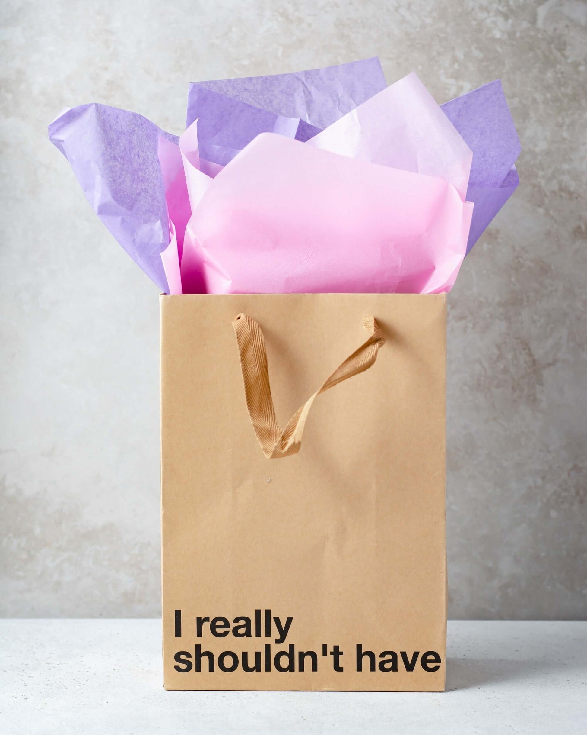 Funny gift bag with the phrase 'I really shouldn't have', featuring colorful tissue paper inside.