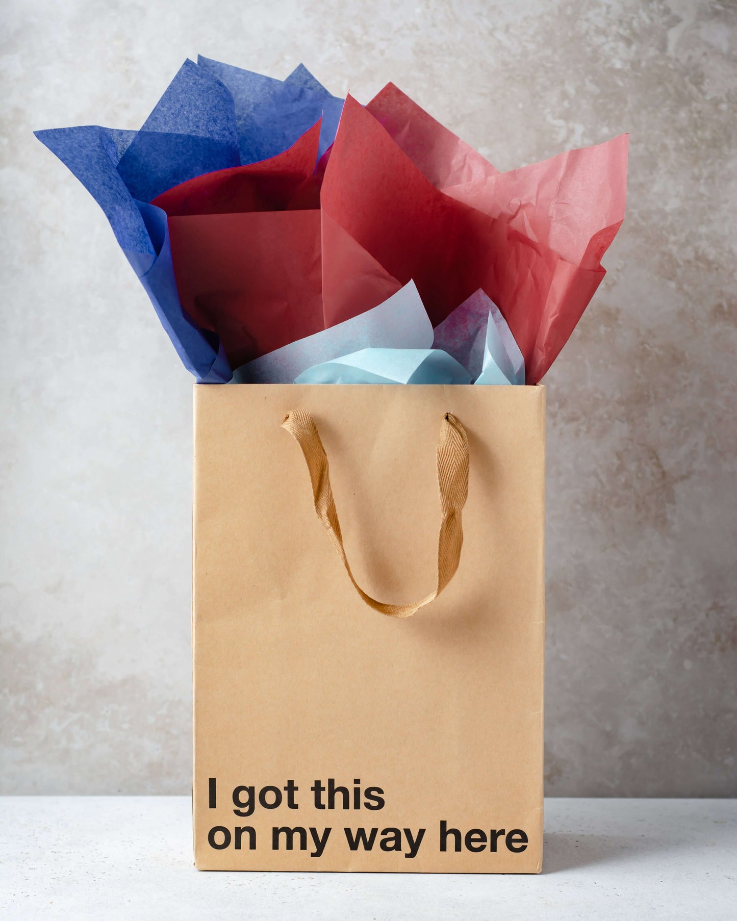 Funny gift bags featuring a kraft bag with the phrase 'I got this on my way here' and colorful tissue paper.
