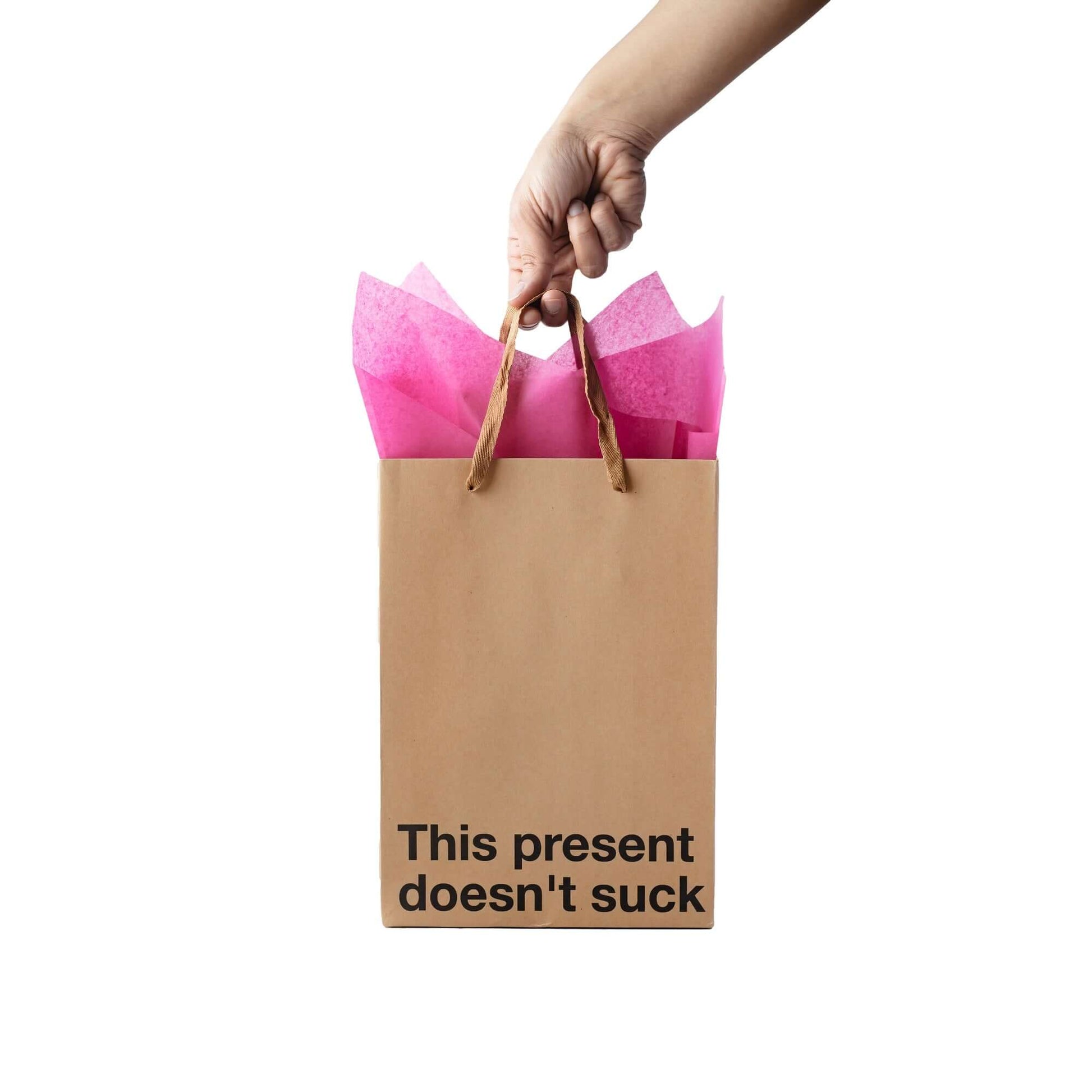 Person holding a funny gift bag that says 'This present doesn't suck' with pink tissue paper inside.
