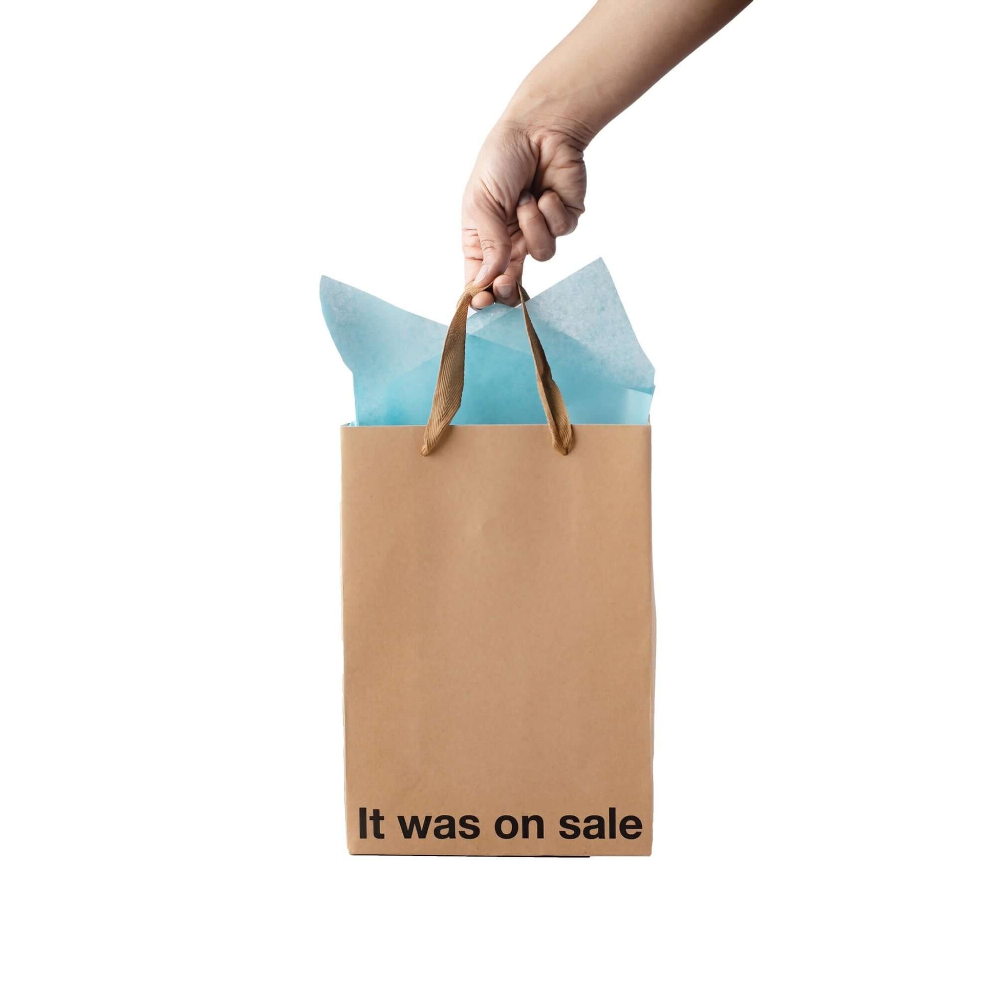 Funny gift bag with brown ribbon handle and blue tissue paper, featuring the text 'It was on sale'.