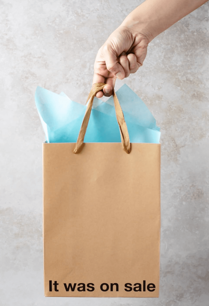 Funny gift bags featuring a brown kraft bag with the text 'It was on sale' and blue tissue paper.