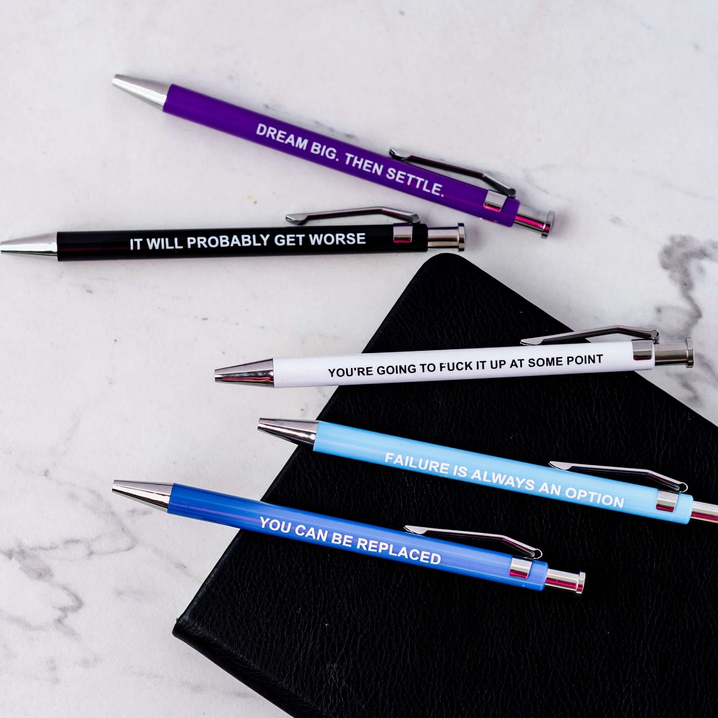 Funny pens featuring demotivational phrases like "You can be replaced" and "Failure is always an option."