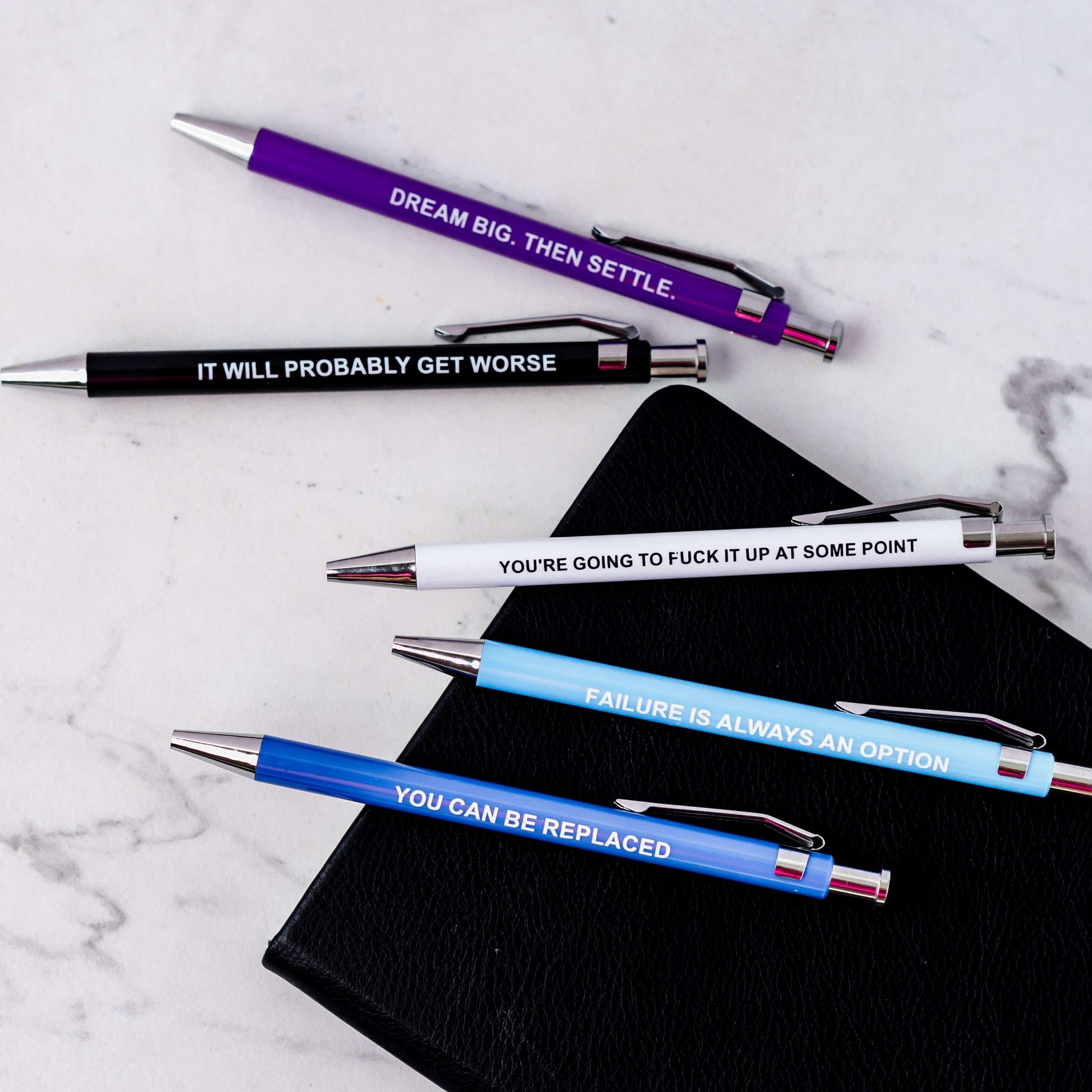 Funny pens featuring demotivational phrases like "You can be replaced" and "Failure is always an option."